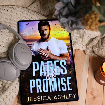 A tablet displaying the audiobook cover of 'Pages of Promise' by Jessica Ashley, styled in a cozy flat-lay setting with gray Bose headphones, a beige knit blanket, and dried flowers.